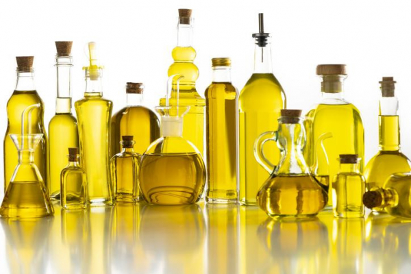 Bottles of all shapes and sizes filled with healthy plant oils posed on a reflective countertop 